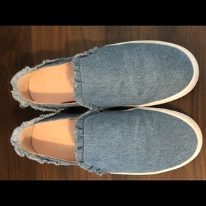 Light blue denim slip-ons with ruffle details.